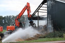 Hooi in schuur vliegt in brand, graafmachines halen hooi uit schuur