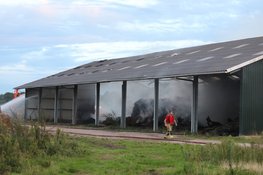 Hooi in schuur vliegt in brand, graafmachines halen hooi uit schuur
